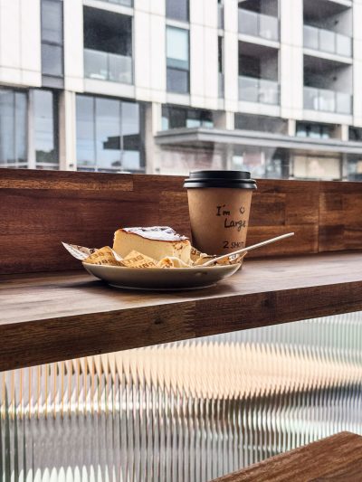 Coffee and cheesecake by the window at Better Burnt café, with timber bar seating.