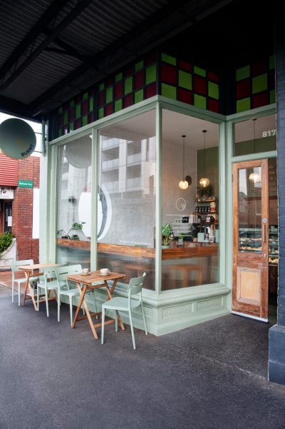 Exterior view of Better Burnt café with sage green shopfront, rustic timber door, and outdoor seating.