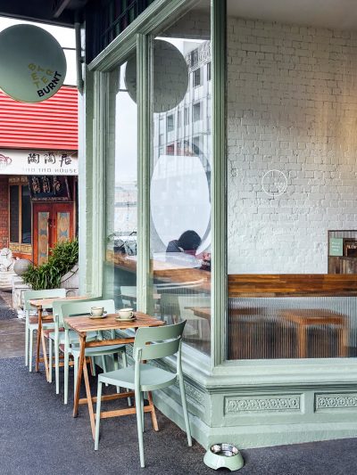 Exterior view of Better Burnt café in London with soft green framing and curbside seating.