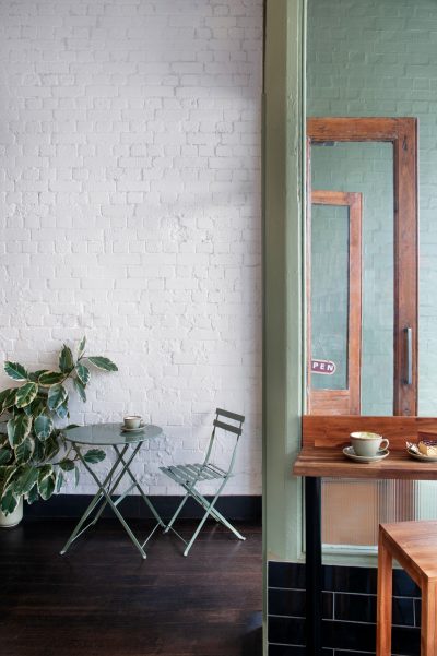 Whitewashed brick walls and compact café seating inside Better Burnt, designed by The Stylesmiths.