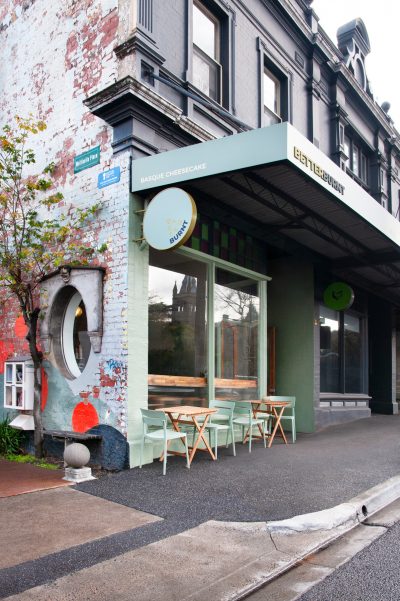 Street view of Better Burnt café with pastel green shopfront and outdoor tables.