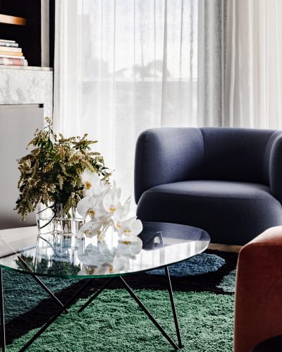 London apartment living room with modern blue armchair, marble finishes, and floral styling.