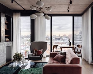 Open-plan London apartment living room with dining space, velvet sofa, and city skyline views.