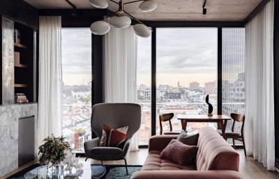 Open-plan London apartment living room with dining space, velvet sofa, and city skyline views.