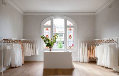 Boutique retail interior in London with arched stained-glass window and minimalist clothing display.