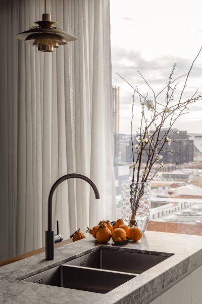 Modern London apartment kitchen designed by The Stylesmiths with marble benchtop and brass pendant light.