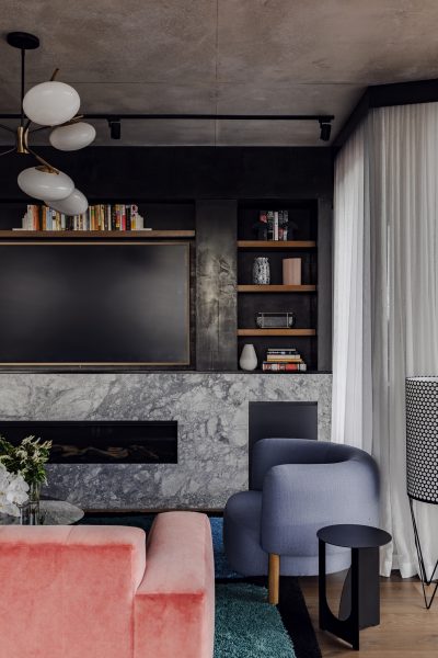 Living room seating area in a London apartment with blush sofa, marble fireplace, and statement lighting.