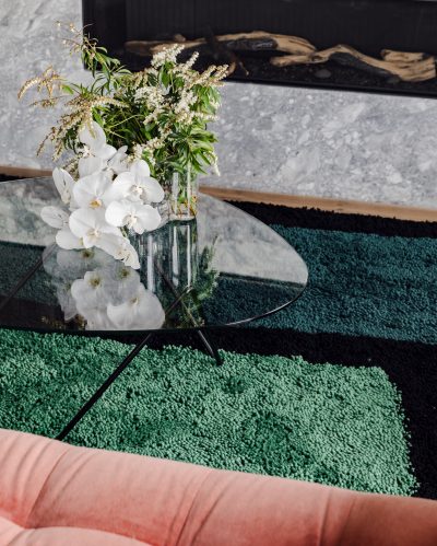 Glass coffee table with fresh floral arrangement in a London apartment living room.