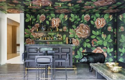 Luxury home bar with floral mosaic wall and modern black furniture in London interior design.