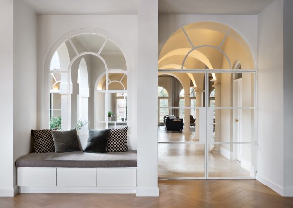 Elegant London interior with arched openings, open-plan flow, and bespoke seating nook designed by The Stylesmiths.