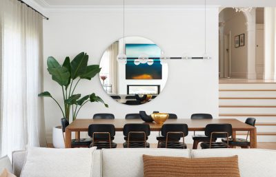 Modern London dining room with round mirror, wooden dining table, and black chairs styled by The Stylesmiths.