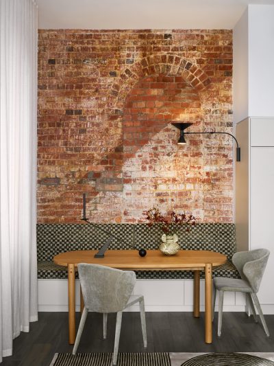 Exposed brick feature wall with custom dining nook and modern lighting in a London home interior.