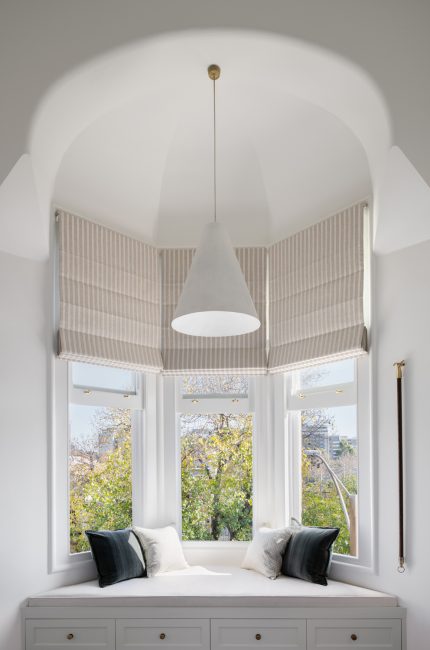 Clapham bay window seat interior with arched ceiling, striped blinds, and soft neutral tones designed by The Stylesmiths London.