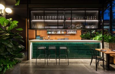 Dalston bar interior with green tiled counter, industrial lighting, and modern seating designed by The Stylesmiths London.