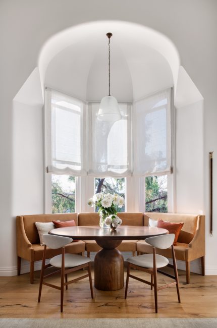 Dalston dining nook with curved banquette, round timber table, and soft natural light designed by The Stylesmiths London.