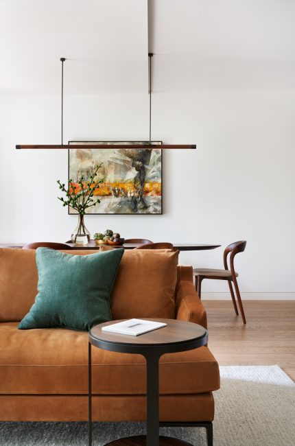 Enfield apartment interior with tan leather sofa, modern artwork, and minimalist styling designed by The Stylesmiths London.
