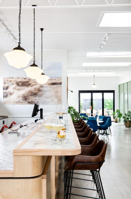 Enfield restaurant and bar interior with marble counter, leather stools, and pendant lighting designed by The Stylesmiths London.