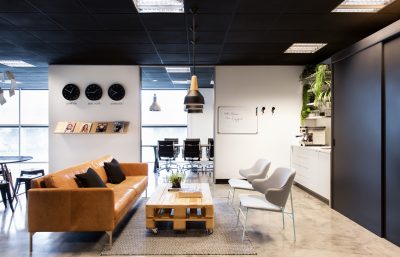 Enfield office interior with tan leather sofa, minimalist workspace, and black ceiling designed by The Stylesmiths London.