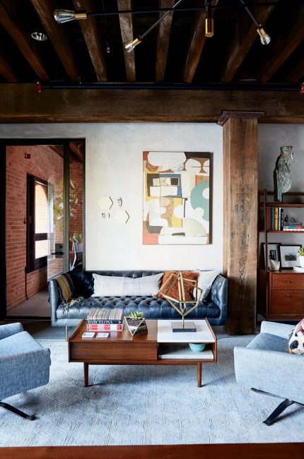 Enfield warehouse office with exposed beams, leather sofa, and abstract artwork designed by The Stylesmiths London.