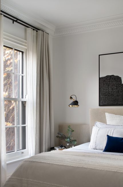 Finsbury bedroom with neutral bedding, textured headboard, and black-and-white artwork designed by The Stylesmiths London.