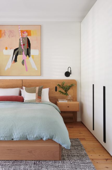 Kentish Town bedroom interior with timber headboard, abstract art, and pastel bedding designed by The Stylesmiths London.
