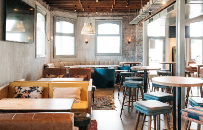Stylish Limehouse bar interior with exposed brick, timber furniture, and pendant lighting by The Stylesmiths London.
