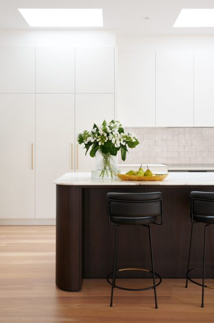 Bright Limehouse kitchen interior with white cabinetry, marble island, and black stools designed by The Stylesmiths London.
