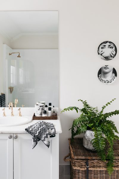 Marble vanity with gold tapware, rattan details, and greenery in a London heritage home designed by The Stylesmiths.