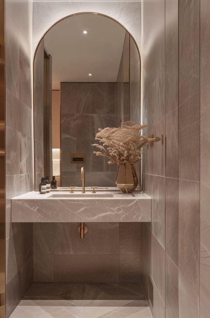 Luxurious Primrose Hill bathroom with marble finishes, arched mirror, and brass tapware by The Stylesmiths London.