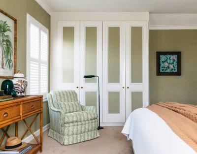 Green patterned armchair and fitted wardrobe in a London heritage home by The Stylesmiths London.