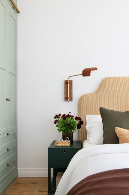 Calm and inviting bedroom in Tottenham with sage cabinetry, brass lighting, and earthy tones by London interior designers.
