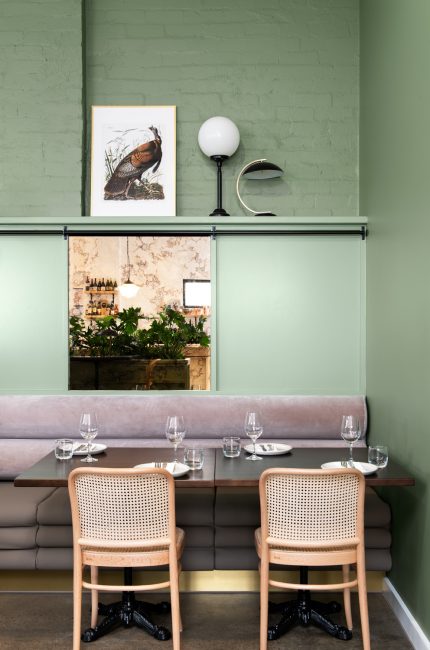 Modern Tottenham restaurant interior with green walls, timber furniture, and intimate dining design.