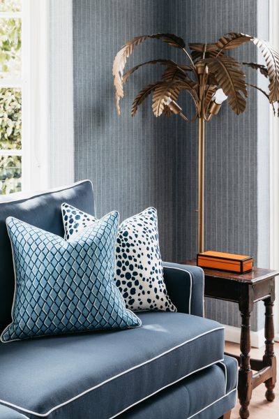 Blue sofa with patterned cushions and gold palm lamp in a London living room designed by The Stylesmiths.