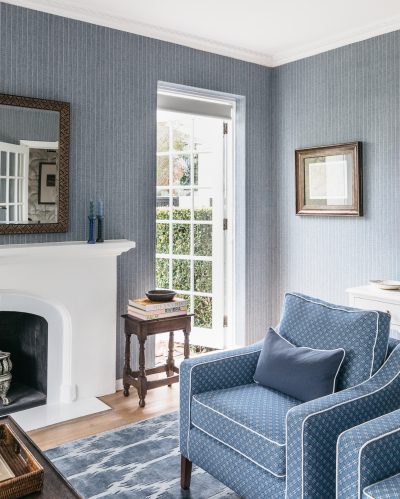 White fireplace and blue armchair with patterned fabric in a London heritage home interior.