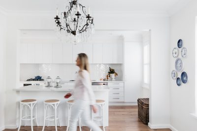 The Stylesmiths London interior designer walking through a white kitchen with chandelier and heritage details.