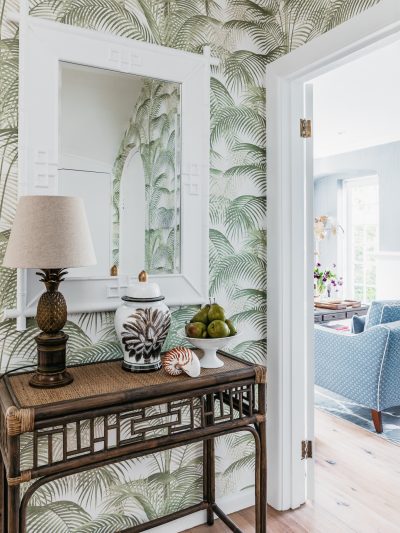 London hallway with palm-print wallpaper, decorative mirror, and natural materials styled by The Stylesmiths London.