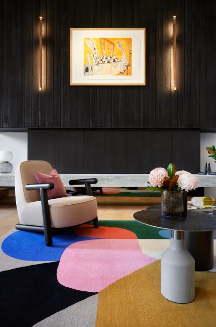 Modern London living room with black timber wall panelling, bold artwork, and colourful rug designed by The Stylesmiths London.
