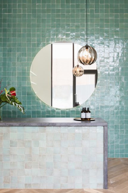 Primrose Hill beauty salon interior with green zellige tiles, round mirror, and pendant lighting by The Stylesmiths London.