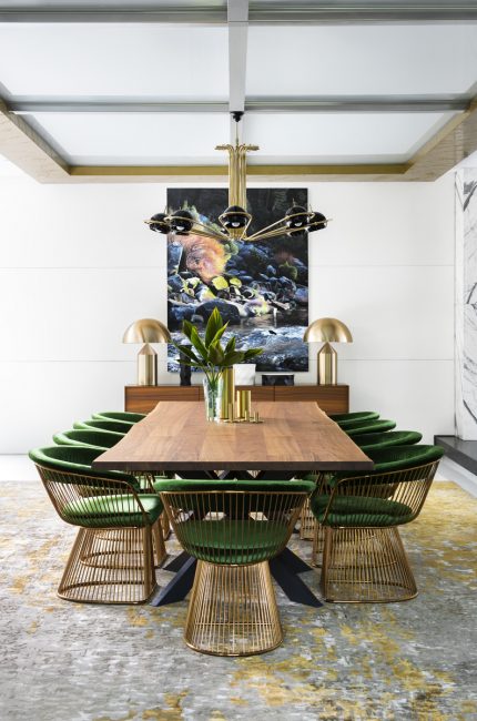 London dining space with green velvet chairs, brass lighting, and contemporary artwork designed by The Stylesmiths London.