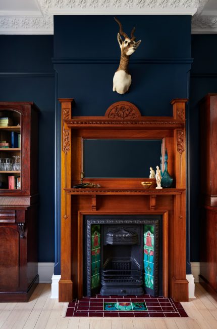 Restored Tottenham heritage home interior with navy walls, detailed wood fireplace, and vintage accents.