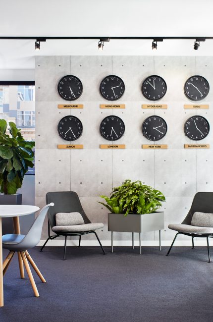 Tower Hamlets modern office interior with world clock wall, grey seating, and natural greenery designed by The Stylesmiths London.