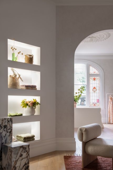 Tower Hamlets retail boutique with arched window, soft plaster walls, and illuminated shelving designed by The Stylesmiths London.