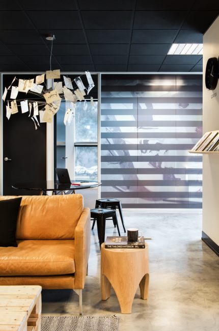 Wembley office interior with tan leather sofa, industrial lighting, and creative workspace design by The Stylesmiths London.