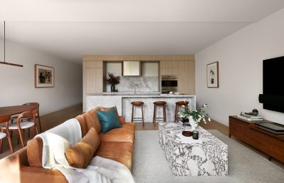 Wembley open-plan living and kitchen interior with marble island, tan leather sofa, and timber finishes designed by The Stylesmiths London.