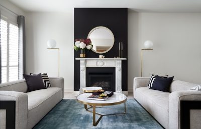 Wimbledon living room with twin sofas, marble fireplace, and black feature wall designed by The Stylesmiths London.