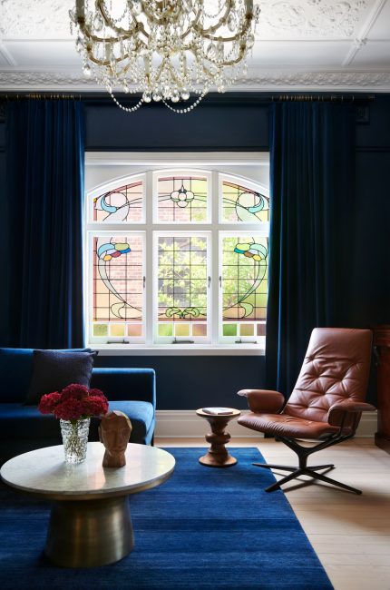 Wimbledon period living room with stained glass windows, crystal chandelier, and blue velvet furnishings designed by The Stylesmiths London.