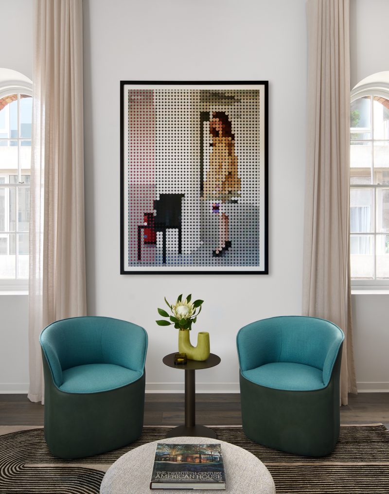 Eclectic London living room with blue armchairs, circular rug, and large modern artwork.