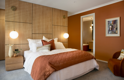 Contemporary London master bedroom with warm terracotta tonality, timber wall panelling and soft ambient lighting by The Stylesmiths.