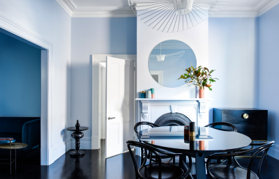 London sustainable dining room with soft blue tonal walls, sculptural pendant lighting and contemporary black dining setting by The Stylesmiths.