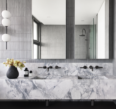 Modern London bathroom with double arched mirrors, grey textured tiles and marble double vanity with matte black tapware by The Stylesmiths.